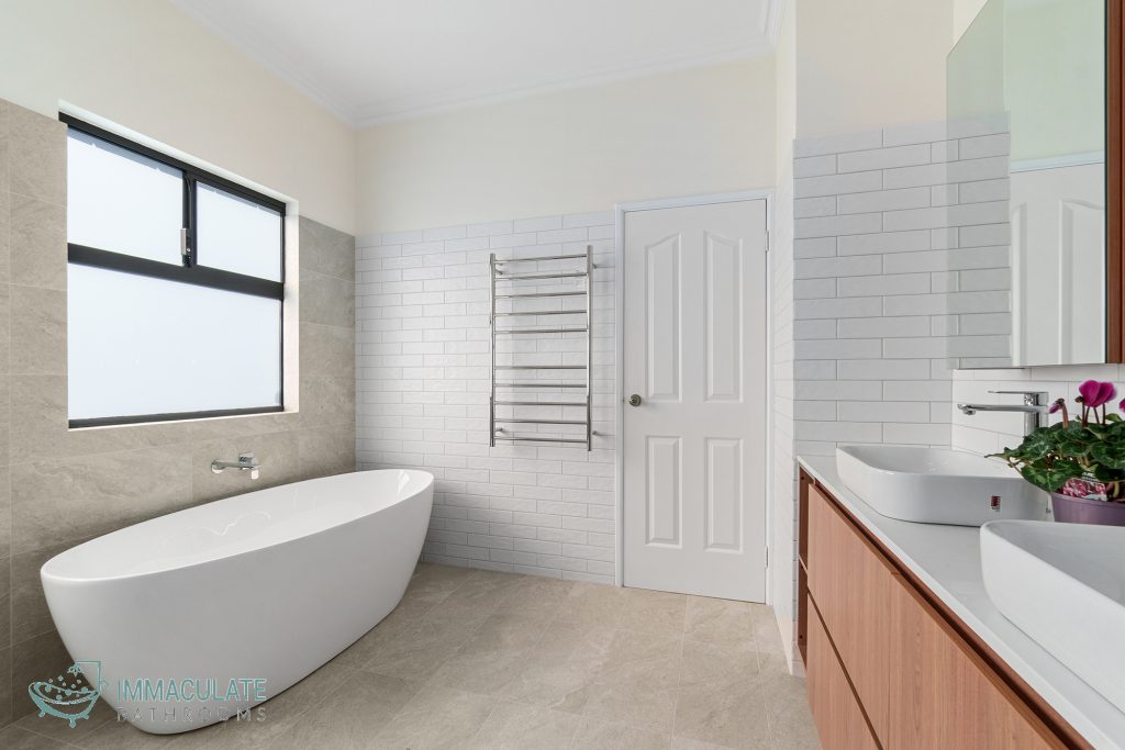 Modern bathroom renovation in Perth featuring freestanding bathtub, tiled walls, double vanity and heated towel rail.