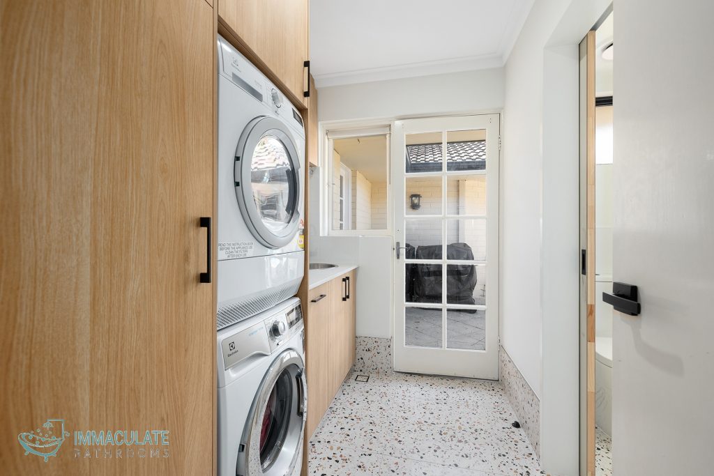 Modern Perth laundry renovation with timber cabinetry, stacked washer dryer, and terrazzo flooring by Immaculate Bathrooms