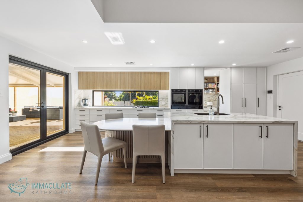 Modern kitchen renovation in Perth featuring marble island benchtop, white cabinetry, and timber flooring by Immaculate Bathrooms Perth.