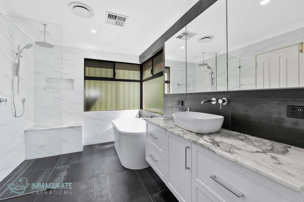 Luxurious modern bathroom renovation in Perth featuring freestanding bathtub, marble vanity, large mirrors, and walk-in shower by Immaculate Bathrooms.