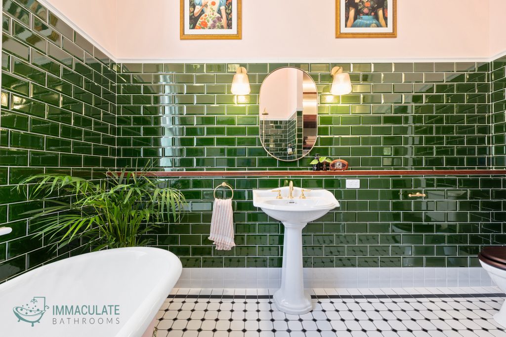 Classic bathroom renovation in Perth featuring deep green subway tiles, white pedestal sink, and gold fixtures by Immaculate Bathrooms Perth.