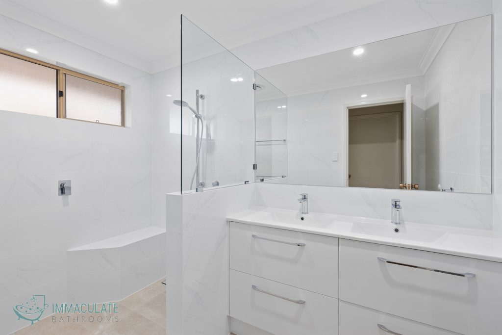 Modern white bathroom renovation featuring double vanity, large wall mirror, walk-in shower with glass screen and built-in bench — Immaculate Bathrooms Perth