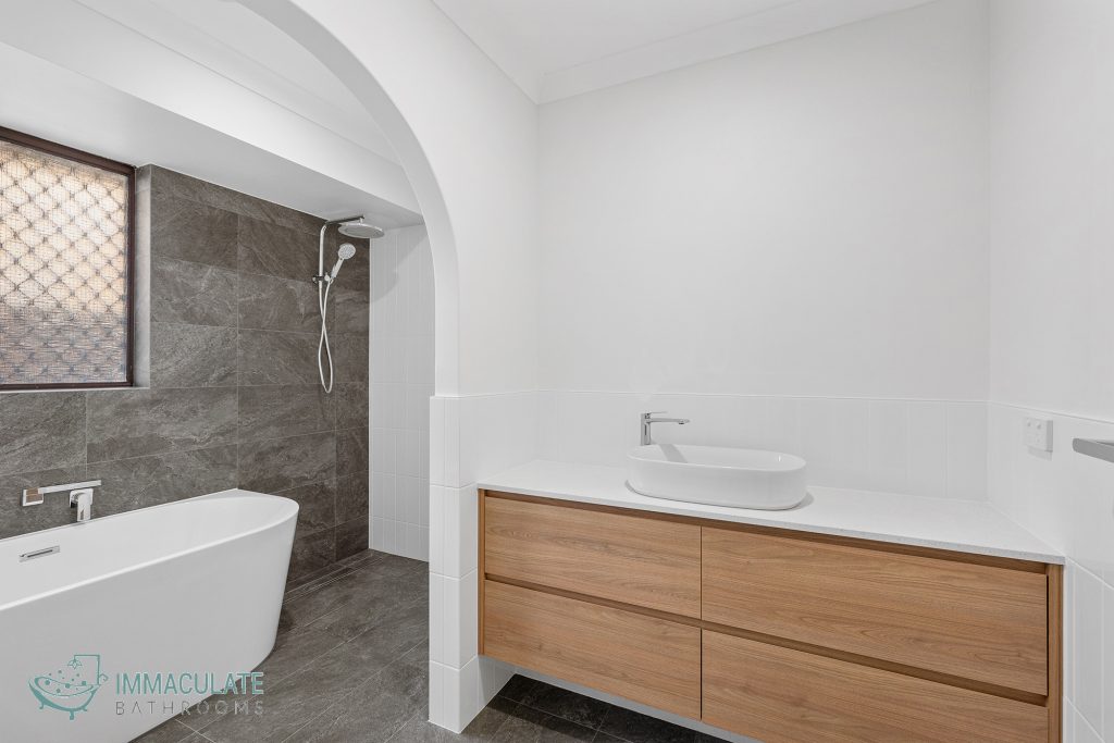 Modern bathroom renovation with freestanding bath, walk-in shower, arched entry and timber vanity.