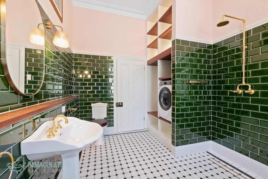 Federation-style bathroom renovation in Perth featuring glossy green subway tiles, brass tapware, pedestal basin, walk-in shower and built-in laundry cabinetry.