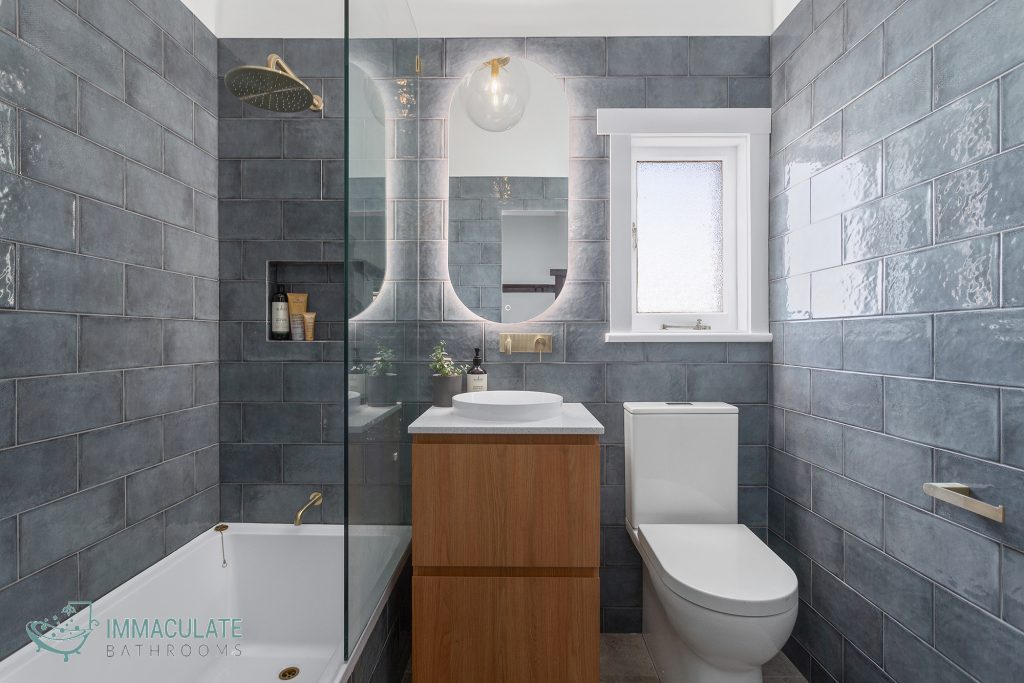 Modern bathroom renovation in Perth featuring blue subway tiles, timber vanity, and gold fixtures by Immaculate Bathrooms Perth.
