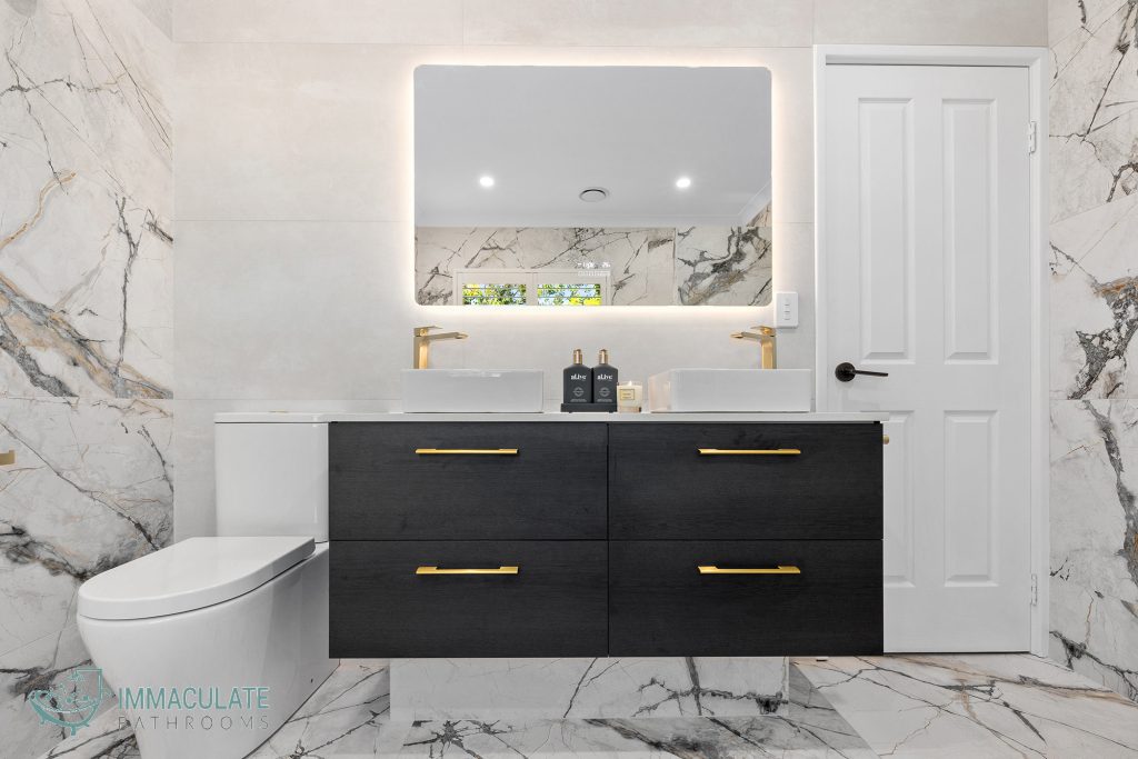 Luxury bathroom with black floating vanity, gold tapware, LED mirror and marble-look tiles by Immaculate Bathrooms Perth