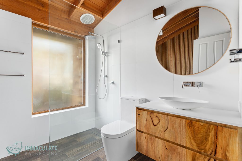 Modern bathroom with timber ceiling, timber floating vanity, round mirror and walk-in shower by Immaculate Bathrooms Perth