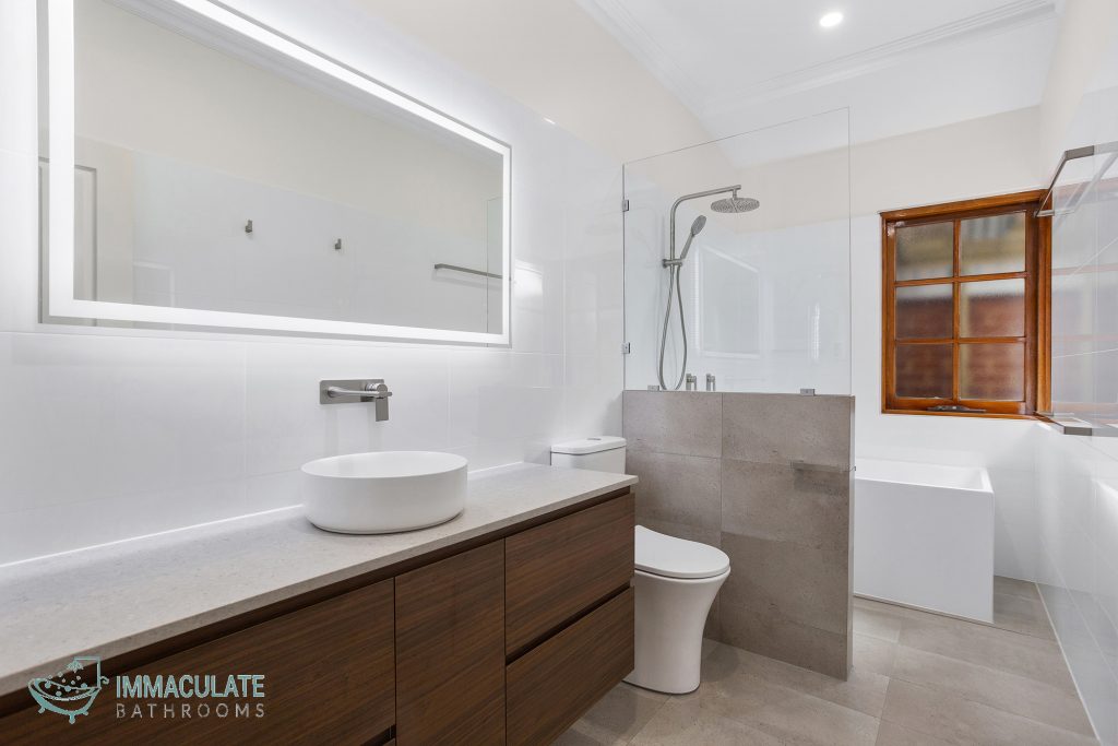 Modern bathroom with LED mirror, timber vanity, freestanding bath and glass shower screen by Immaculate Bathrooms Perth