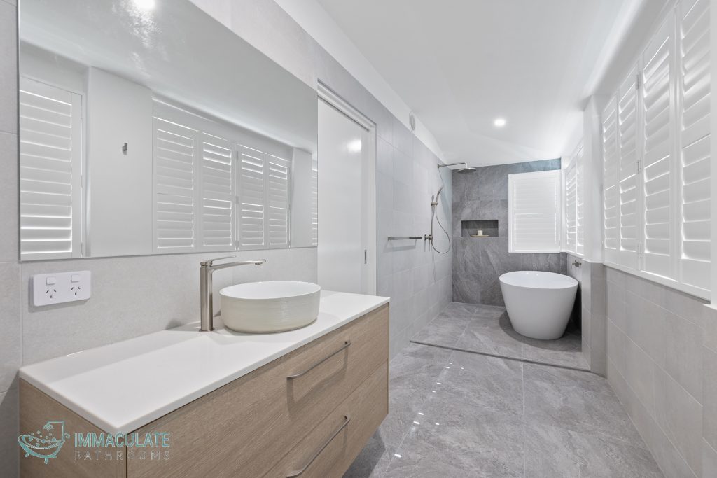 Modern grey-tile bathroom with freestanding bath, floating timber vanity and walk-in shower by Immaculate Bathrooms Perth