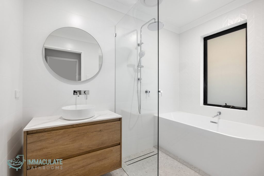 Modern Leederville bathroom with round mirror, timber vanity, walk-in shower and freestanding bath by Immaculate Bathrooms Perth