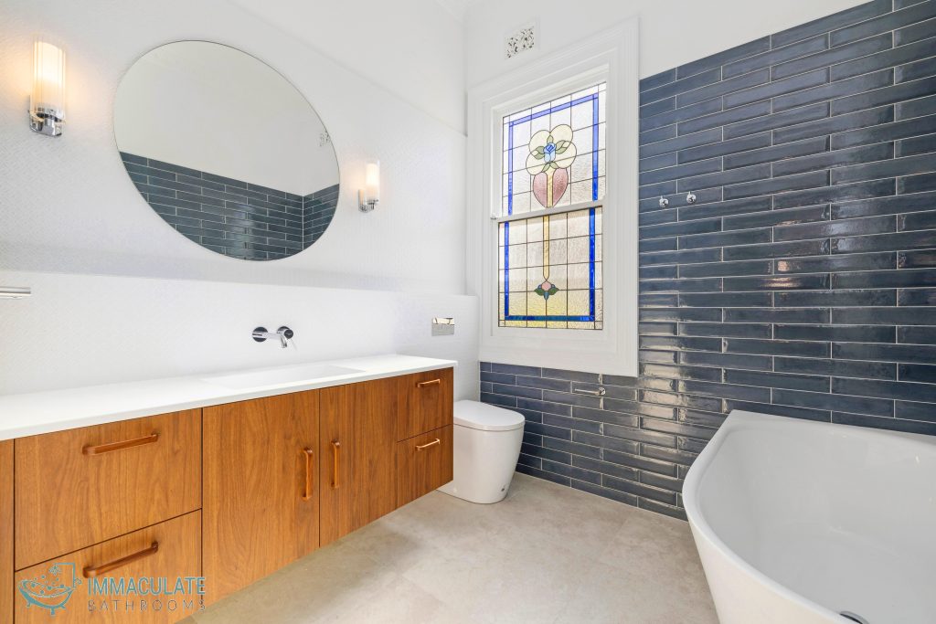 Modern bathroom renovation with timber vanity, blue tiled wall and freestanding bath in Perth